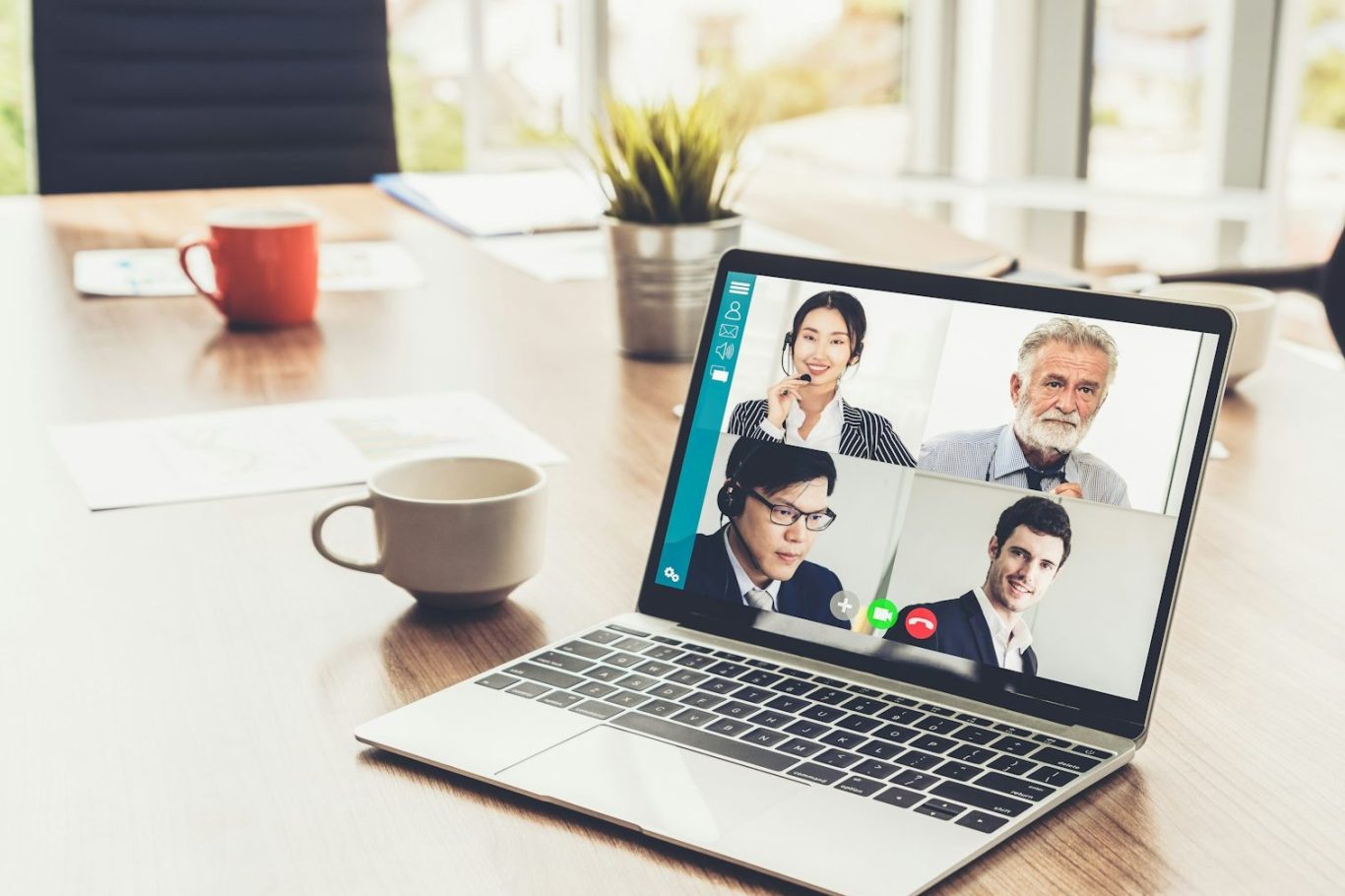 Videokonferenz mit mehreren Teilnehmern auf einem Laptop in einem modernen Büro.