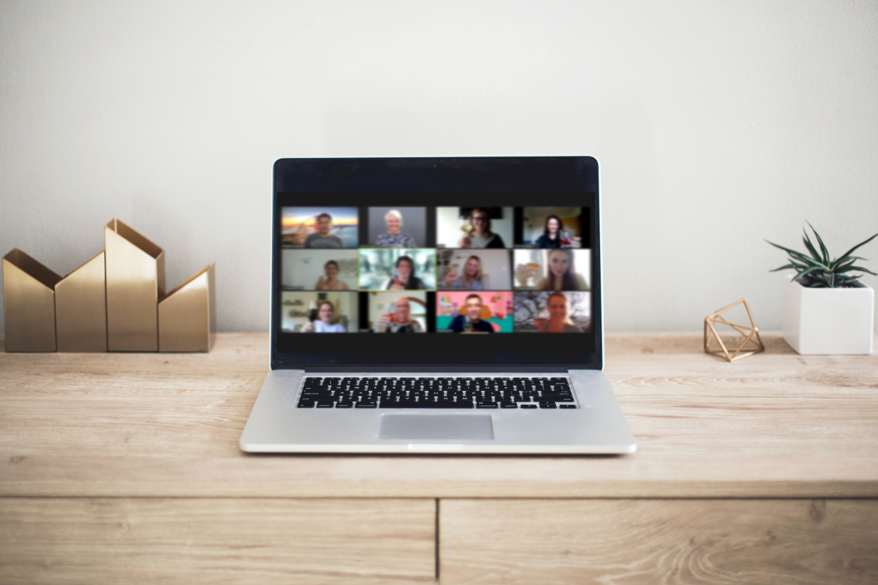 Laptop auf einem Tisch, zeigt eine Videokonferenz mit mehreren Teilnehmern.