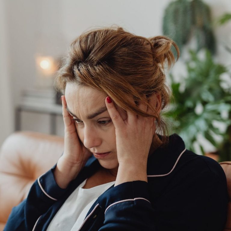 Eine lachende Frau mit Sonnenbrille entspannt am Pool.